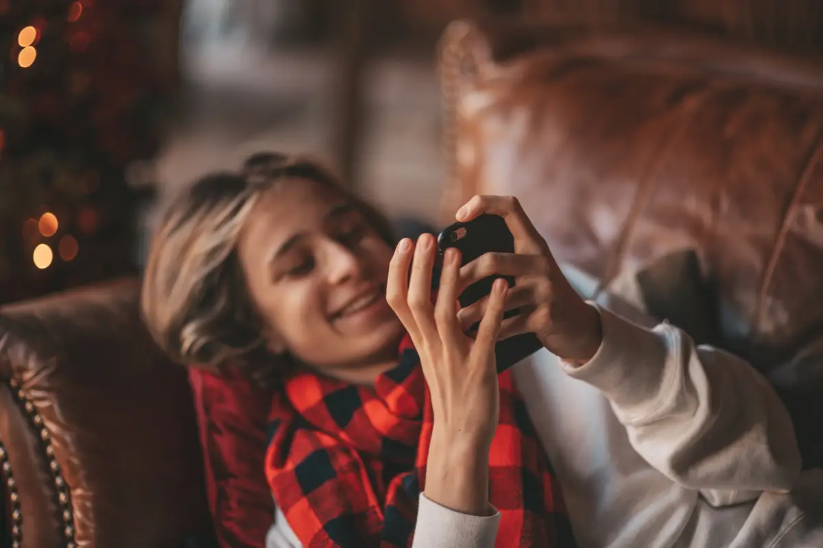 Portrait of candid authentic smiling boy teenager having fun emotion at wooden lodge xmas decorated