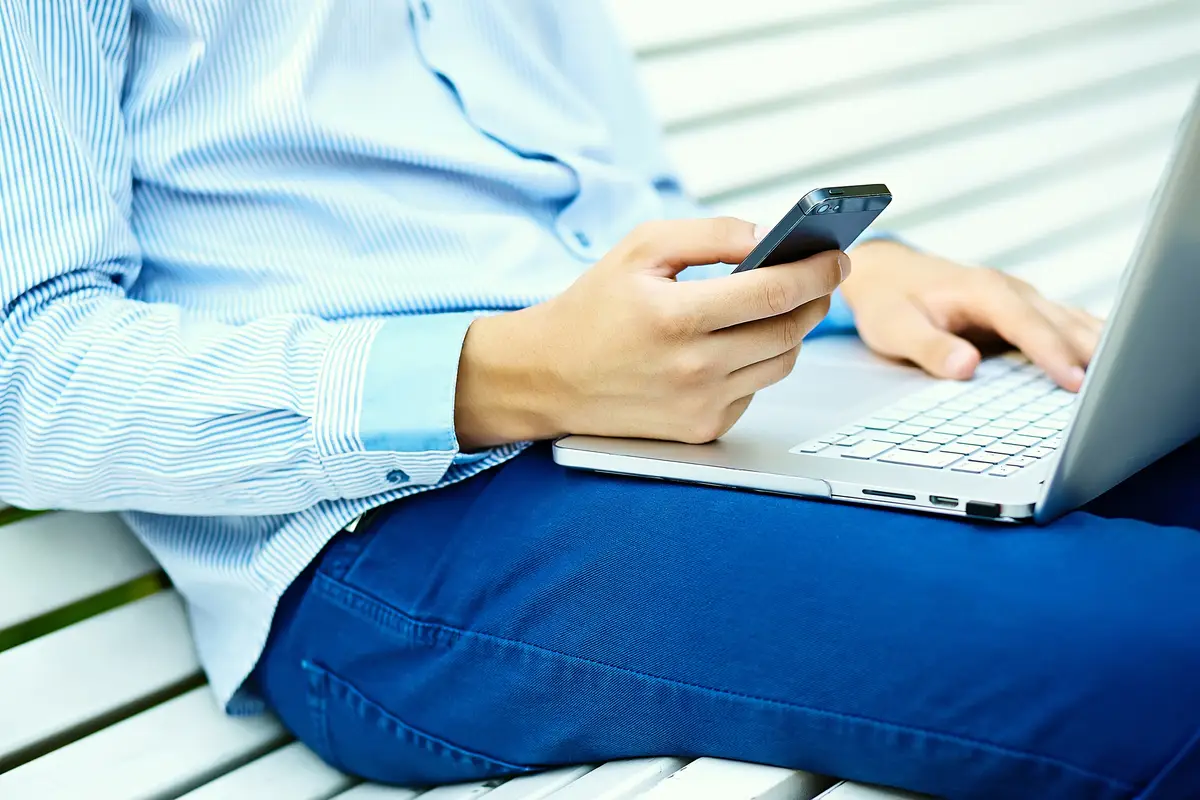 Young man working with laptop, man's hands on notebook computer, business person in casual clothes in the street