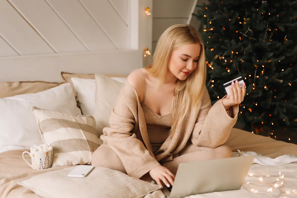 Beautiful young woman shopping online orders christmas gift boxes at home on holiday