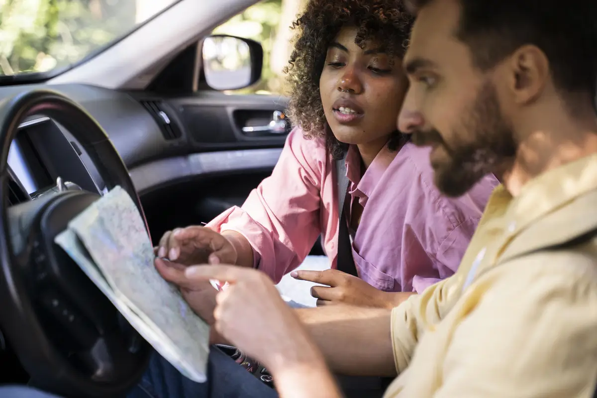 Side view of couple in car consulting map