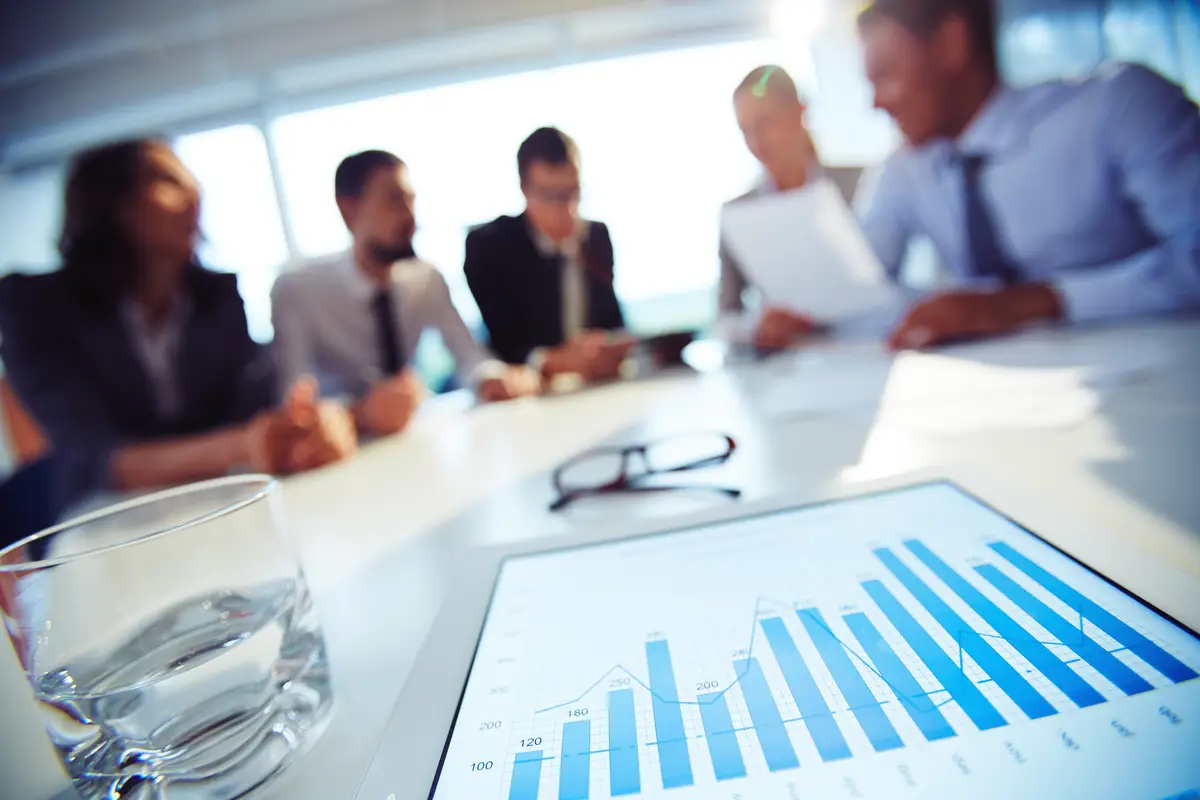 Close-up of glass of water and tablet with executives background