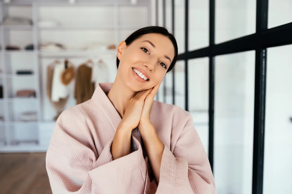 Portrait of a beautiful healthy woman in bathrobe posing at camera indoors