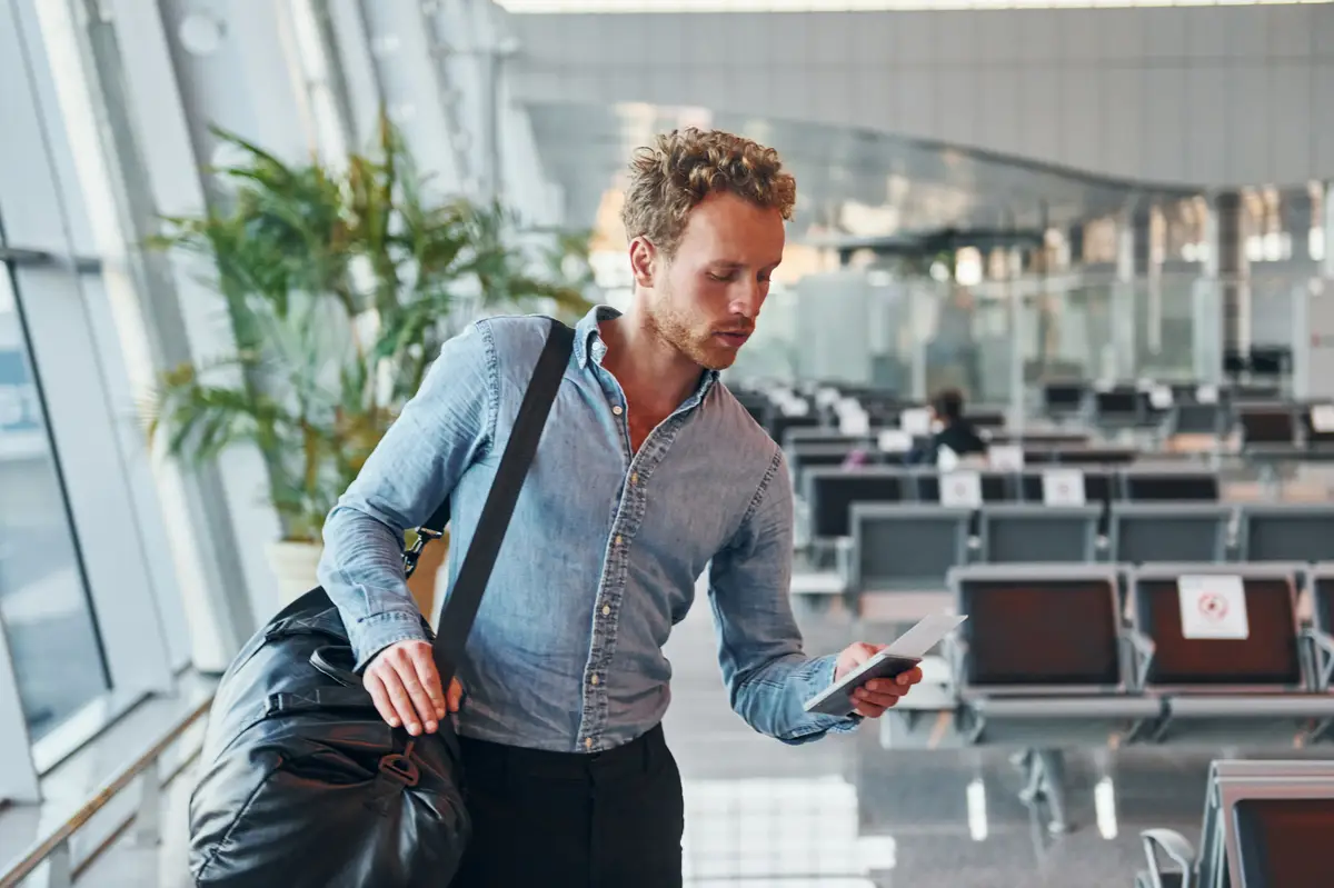 Young man in formal wear is in modern airport Conception of vacation