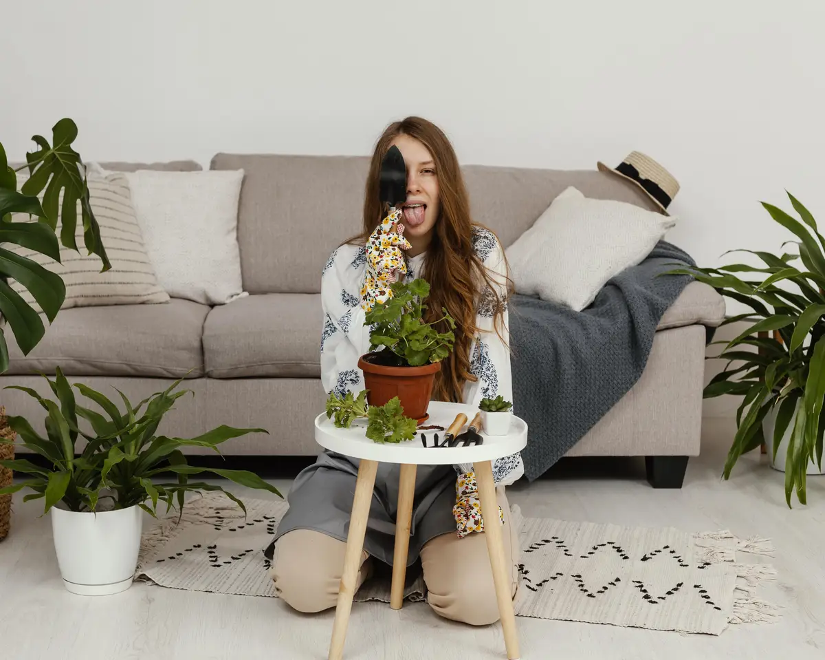 Young woman posing at home with pot of plant and gardening tool