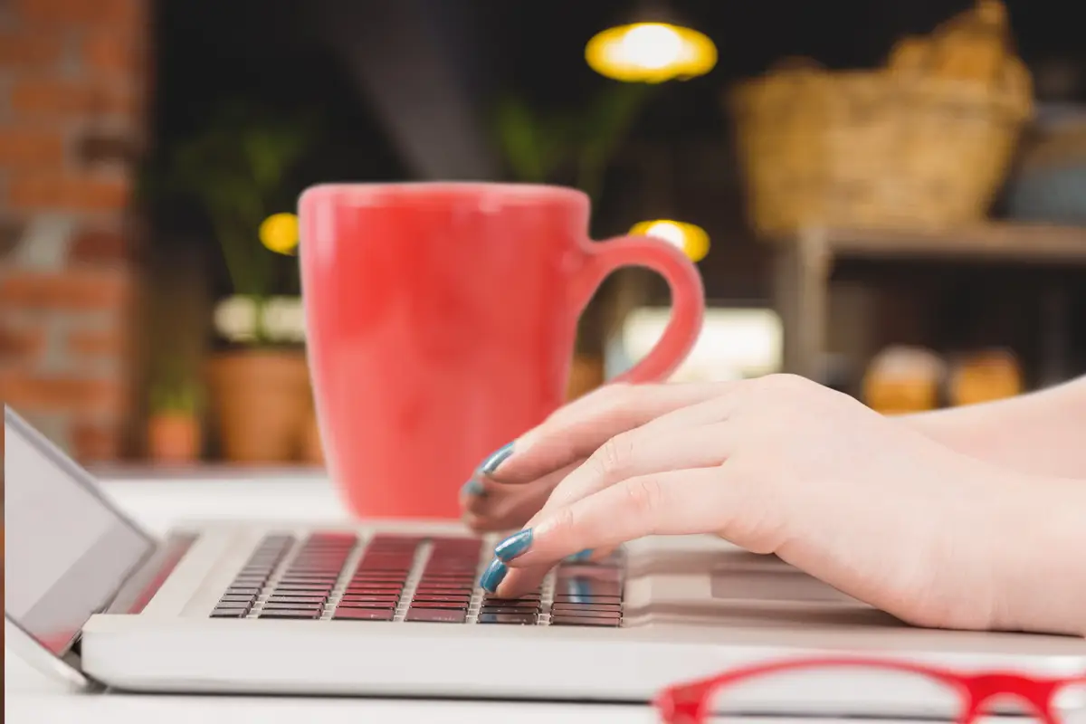 Close-up of woman with painted nails working with her laptop