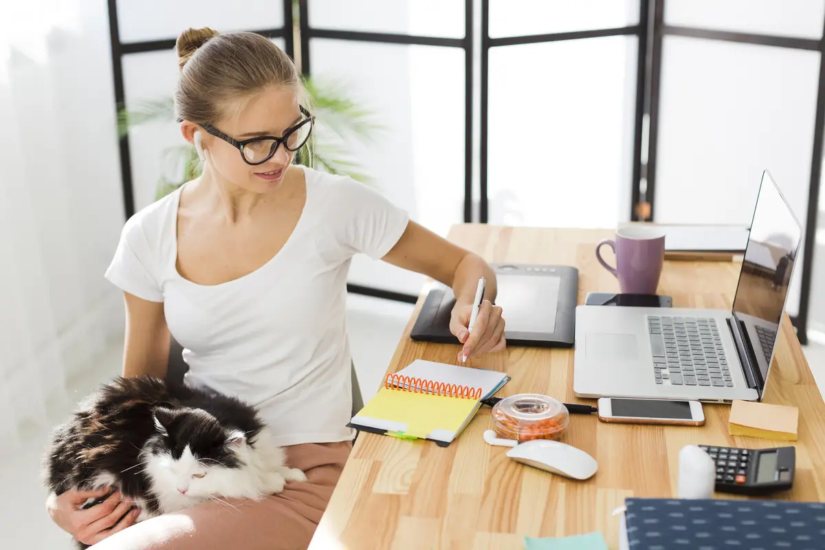 Front view of woman holding cat and working from home