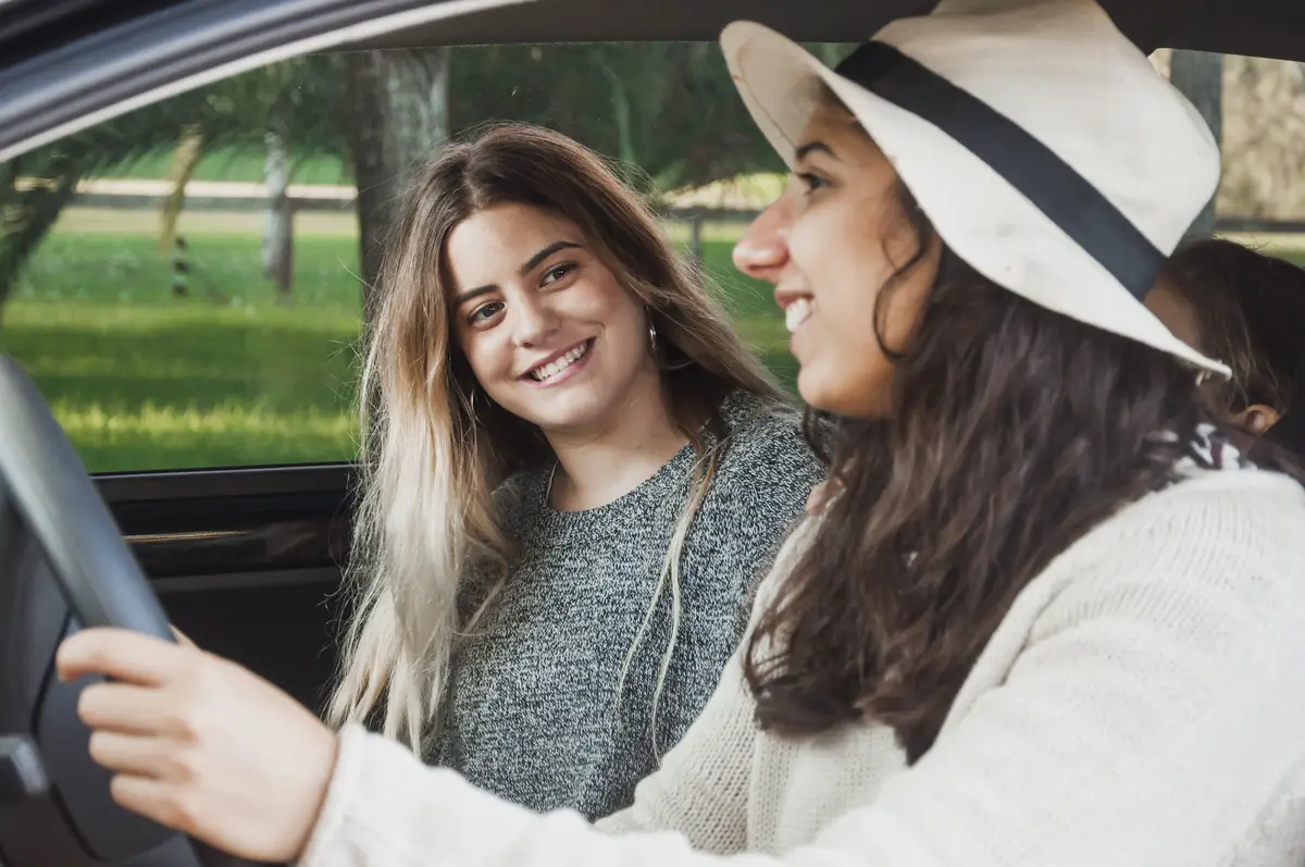 Teenage sisters sitting together inside car