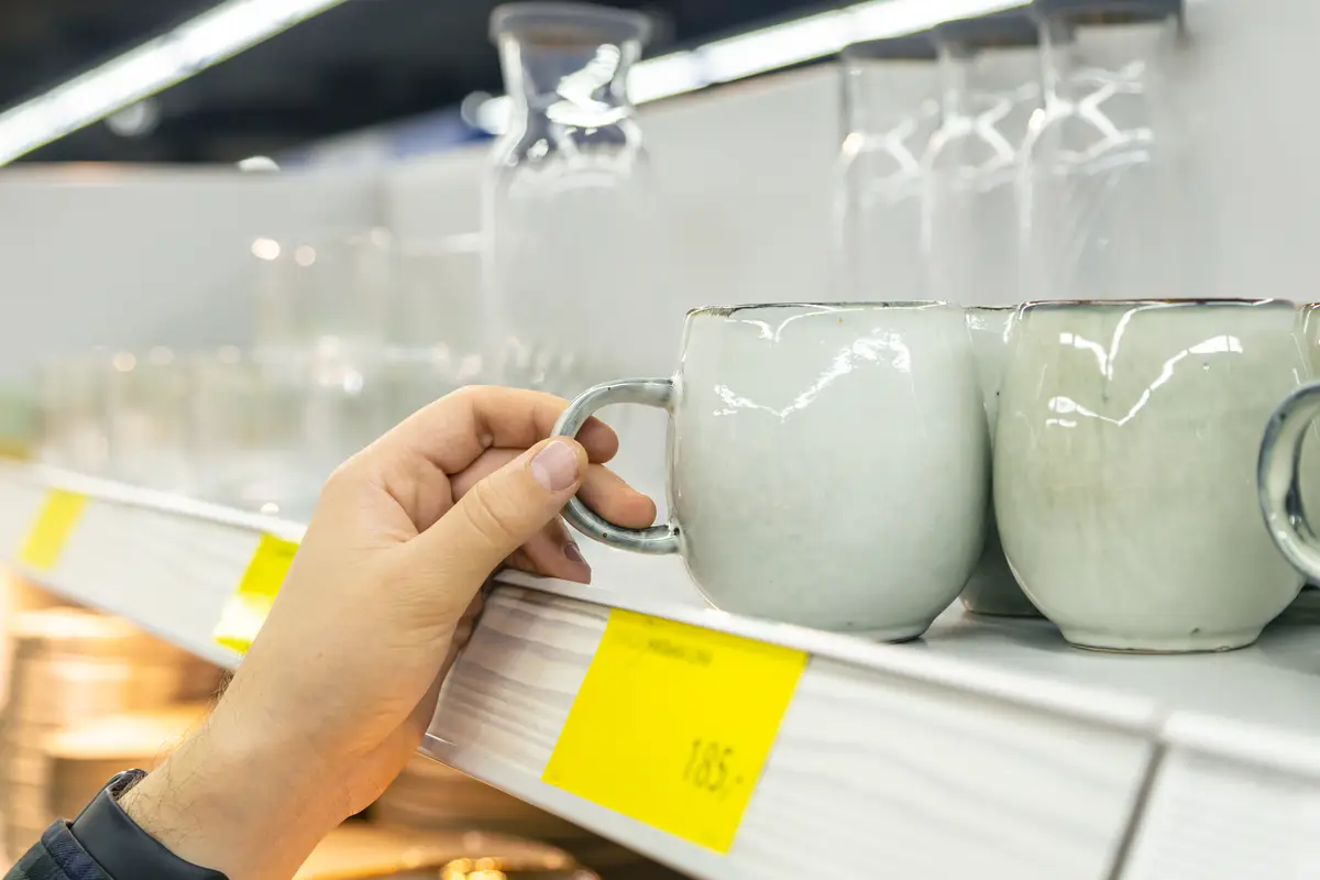 Man holding cup from a shelf in homeware store