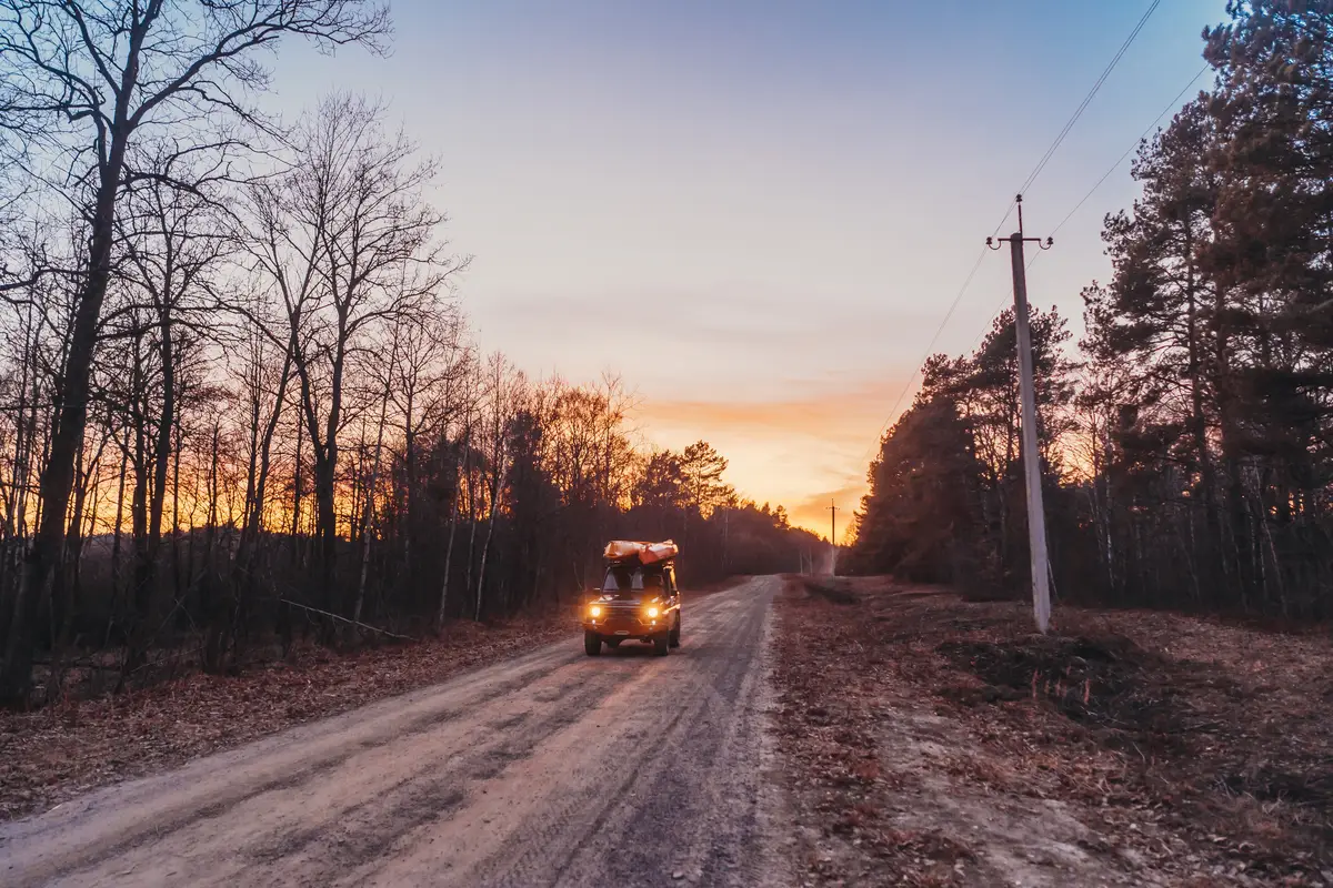 SUV rides on a dirt road at evening