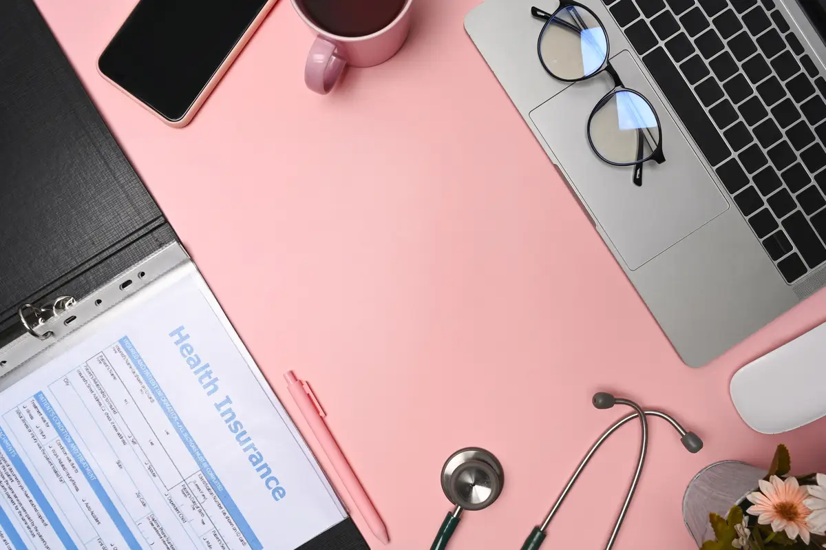 Above view doctor workspace with reports, stethoscope, laptop and smart phone.