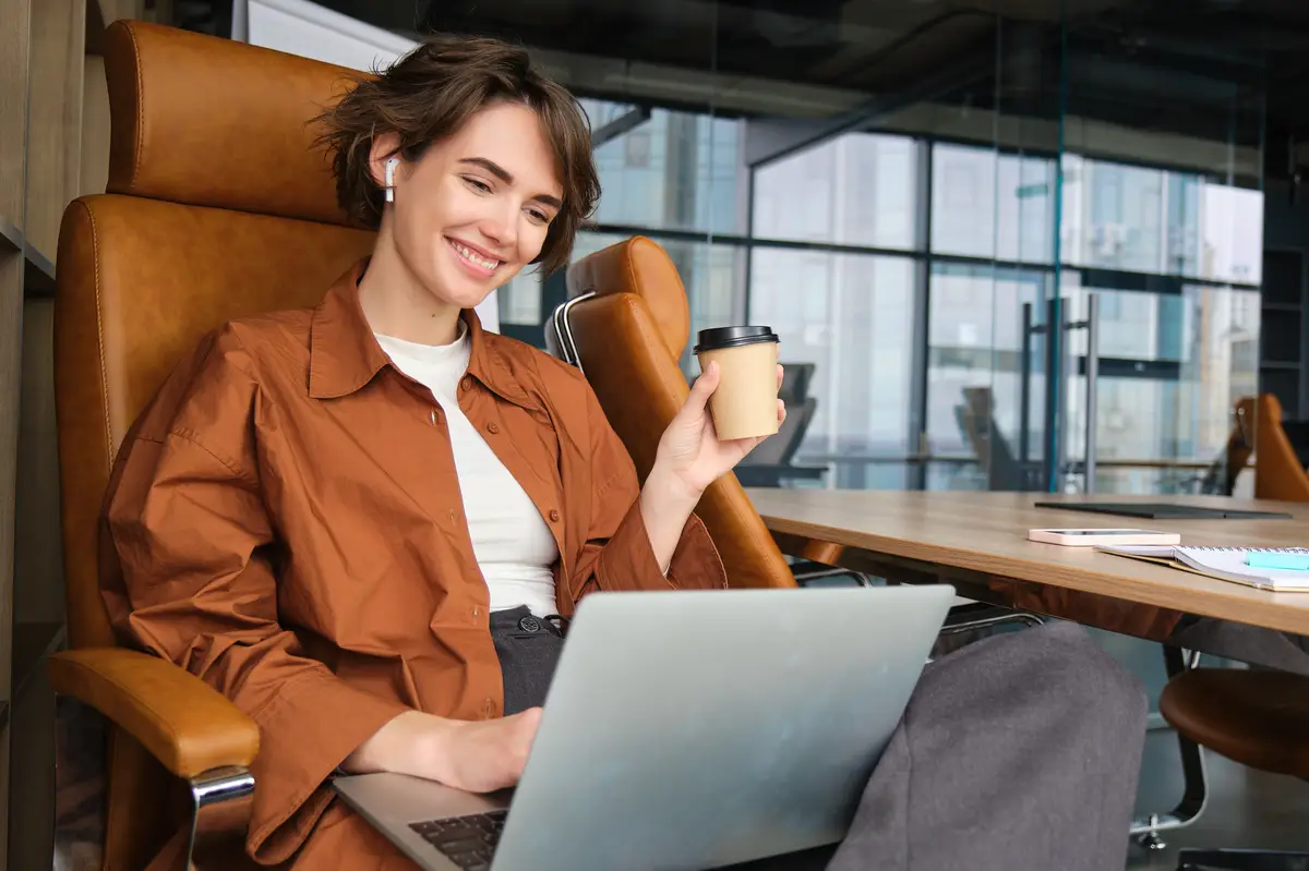 Young woman in coworking space employee sitting in office and working with laptop wearing casual
