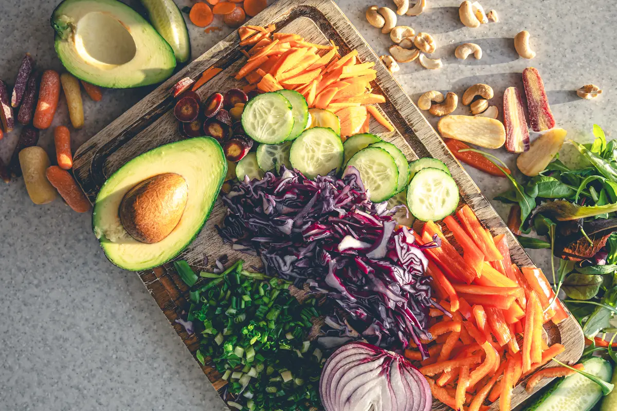 Sliced fresh vegetables on a cutting board on the kitchen table top view