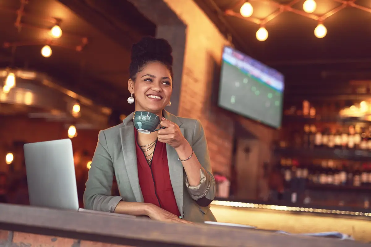 Taxpayer ID nos EUA: Guia Rápido para Brasileiros 2 Business woman coffee and laptop at restaurant with freelancer and remote work with smile Tech tea and bar with online digital and web consultant thinking at cafe table with drink and internet