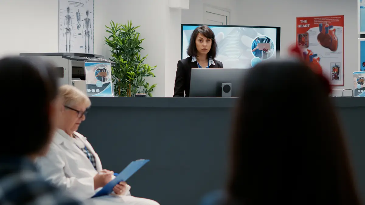 Portrait of hospital receptionist working at administrative counter to help patients with appointments. Female secretary giving support for healthcare at reception desk facility.