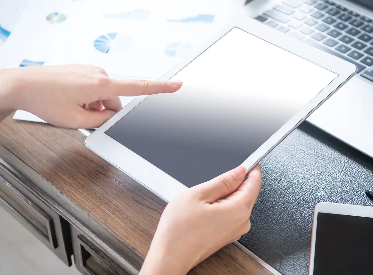 Business concept Woman using tablet for project with digital device in office desk Backlighting sun glare effect close up side view copy space