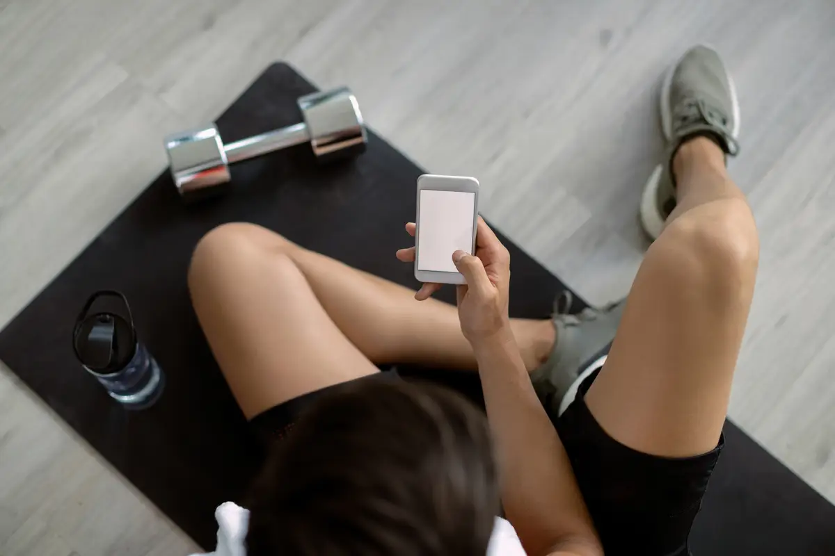 Above view of athlete using cell phone in health club