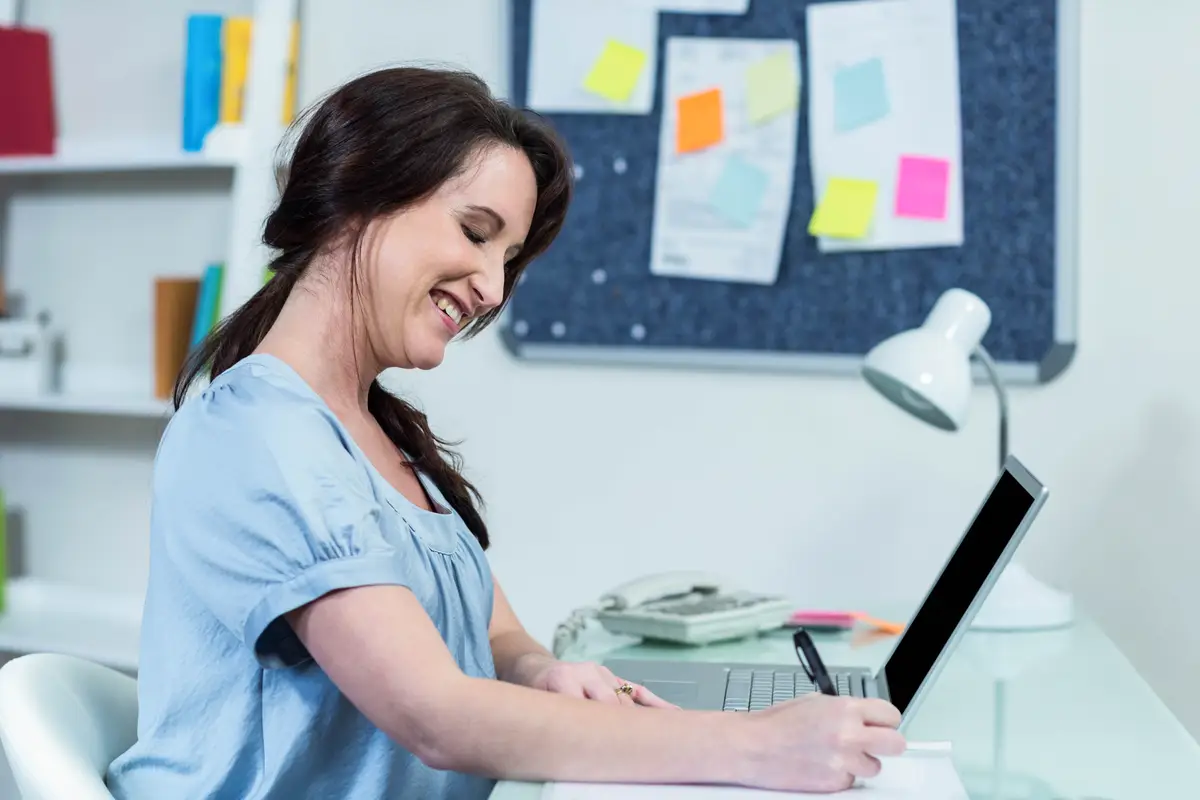 Pregnant woman taking notes at desk 