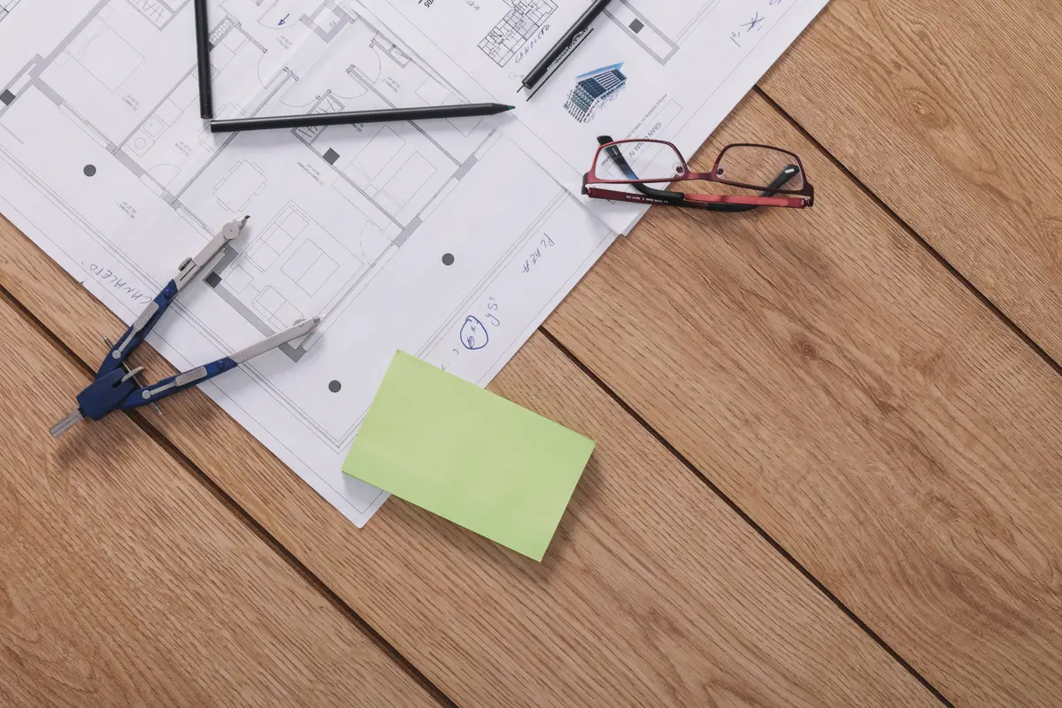 Compasses and sticky notes near glasses and drafts