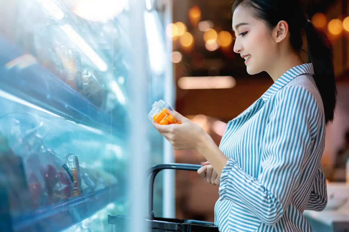 Asian attractive female shopping with happiness and cheerful on supermarket blur mall bokeh backgroundoung Asian woman with cart grocery shopping for fresh produce