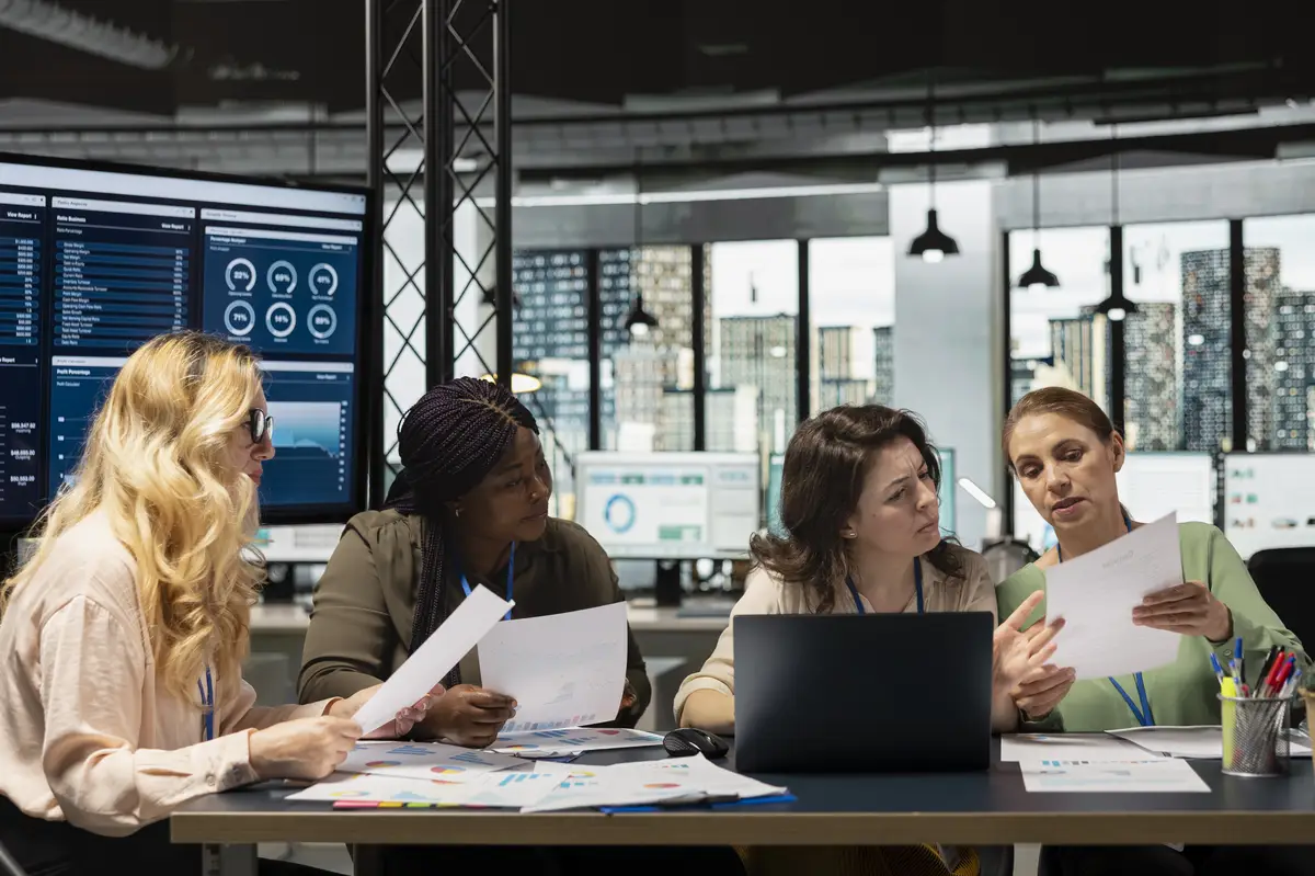 Group of empowered businesswomen collaborate in a modern office reviewing data performance