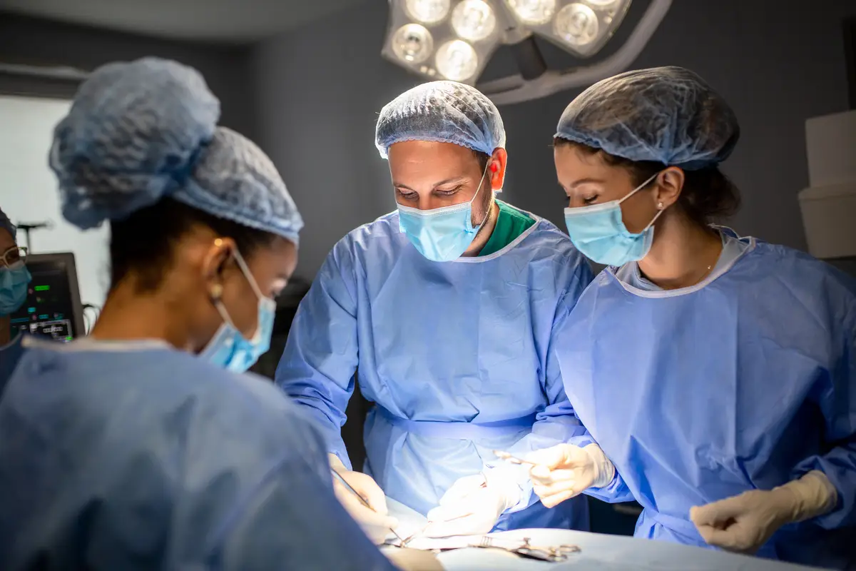 Abordagem das infecções em próteses mamárias: explante ou salvamento 1 Group of surgeons doing surgery in hospital operating theater Medical team doing critical operation Group of surgeons in operating room with surgery equipment Modern medical background