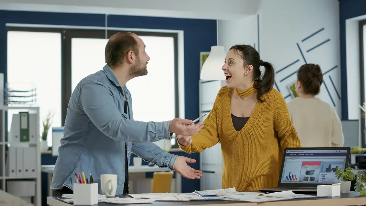 Smiling colleagues in startup office doing high five hand gesture celebrating business success standing at desk. Happy coworkers enjoying good results of team work looking at laptop with charts.