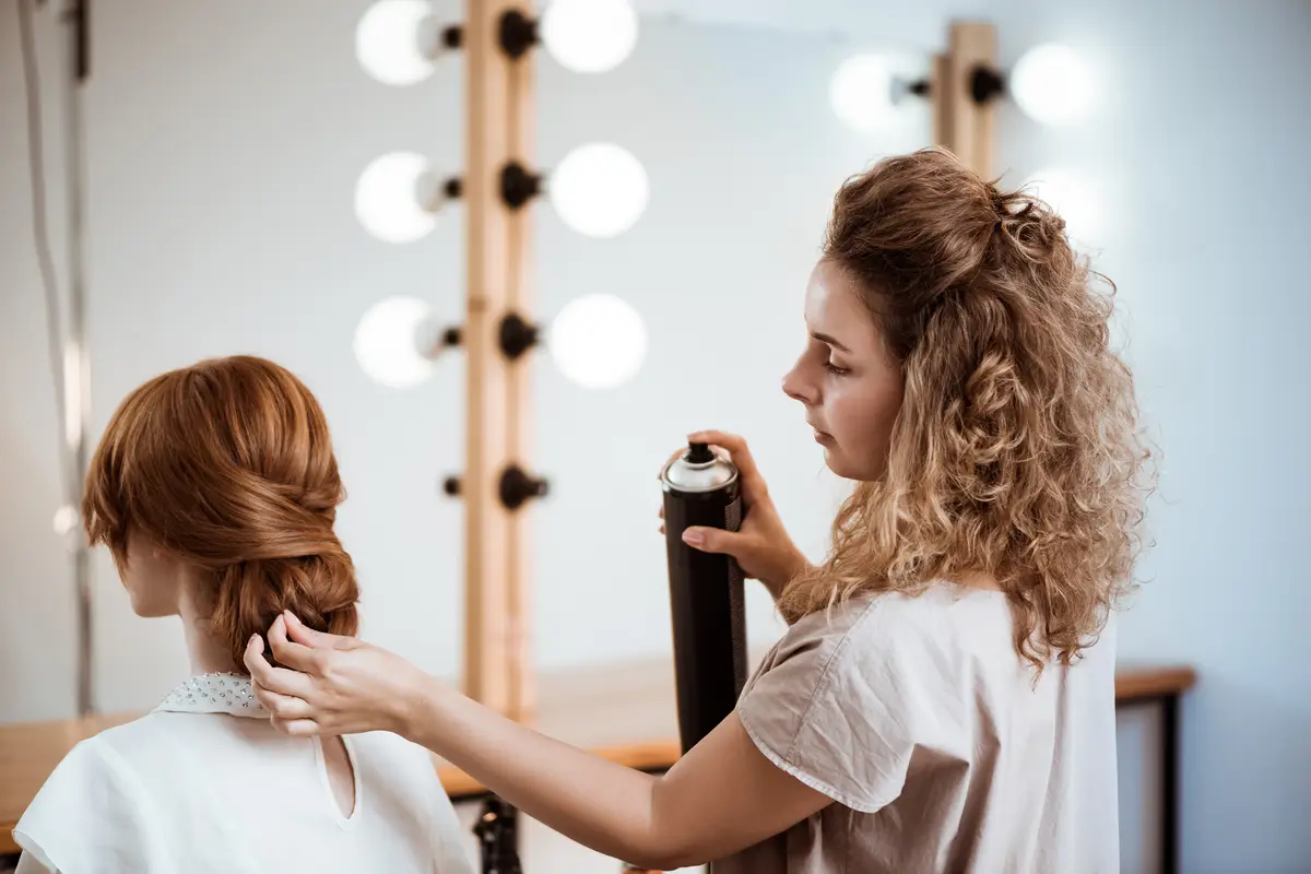 Female hairdresser making hairstyle to redhead woman in beauty salon