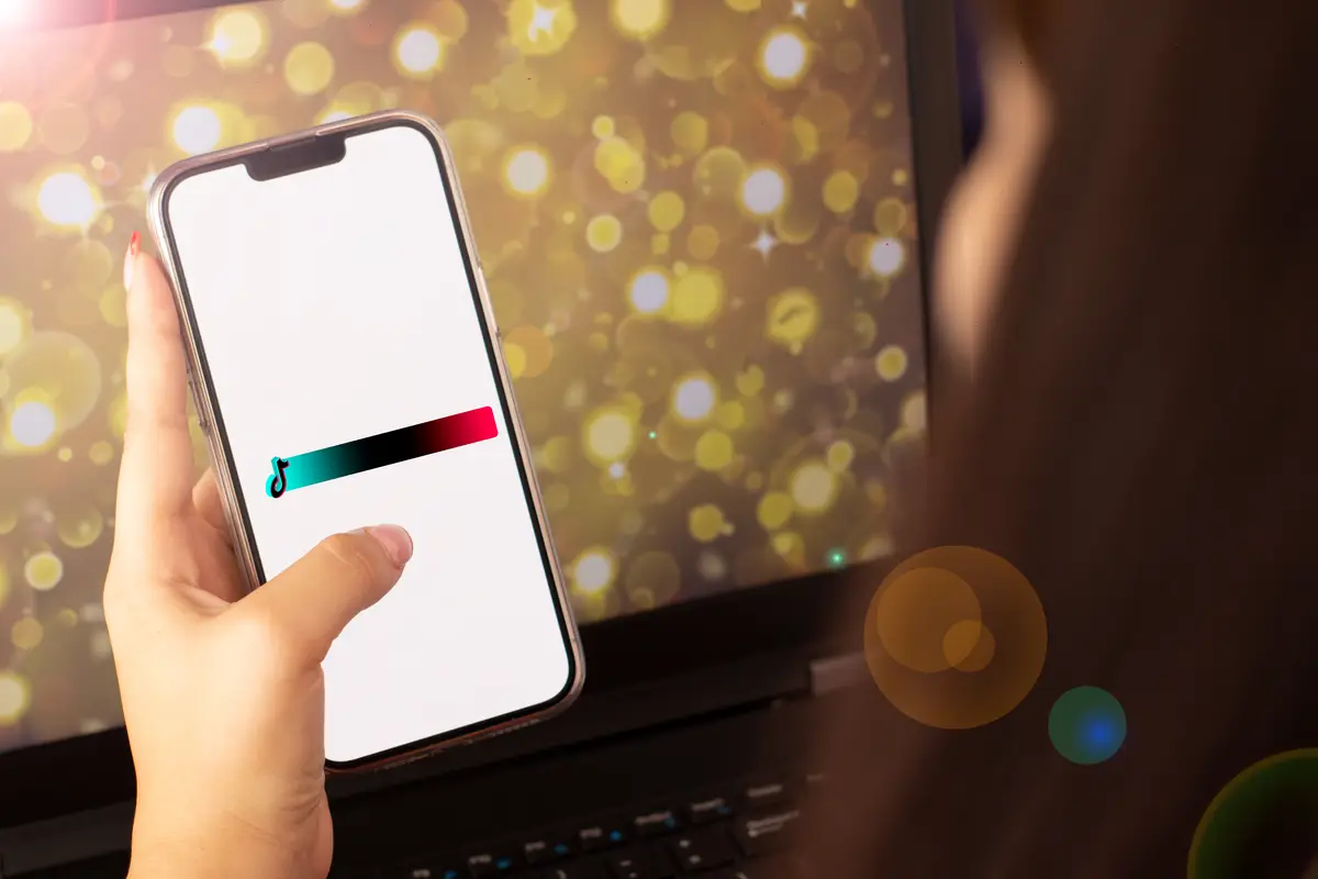 Beautiful hand of a woman holding a cell phone with a tiktok banner