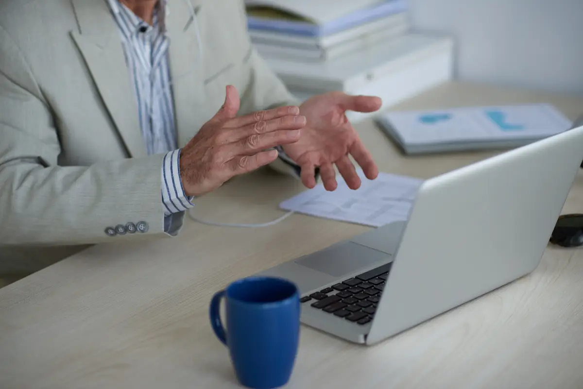 Hands of unrecognizable man having video call on laptop and applauding
