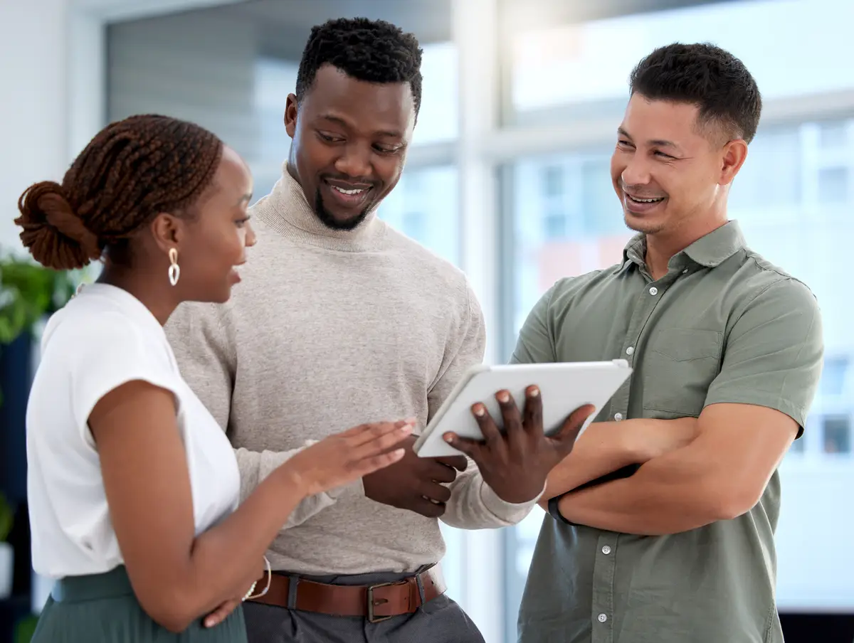 Team men and woman in pointing at tablet smile and review for performance in company Diverse businesspeople and coworkers in global corporate and startup in collaboration for digital or tech