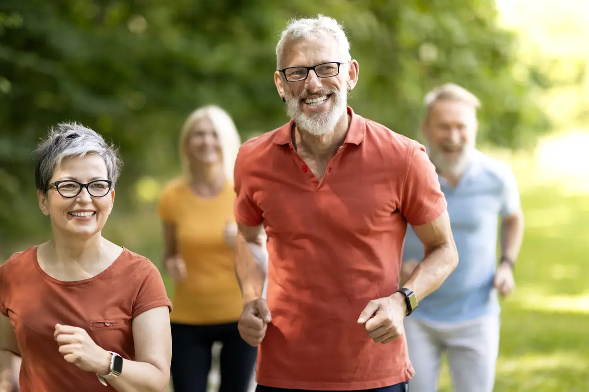 Group of active senior people running together outdoors in park