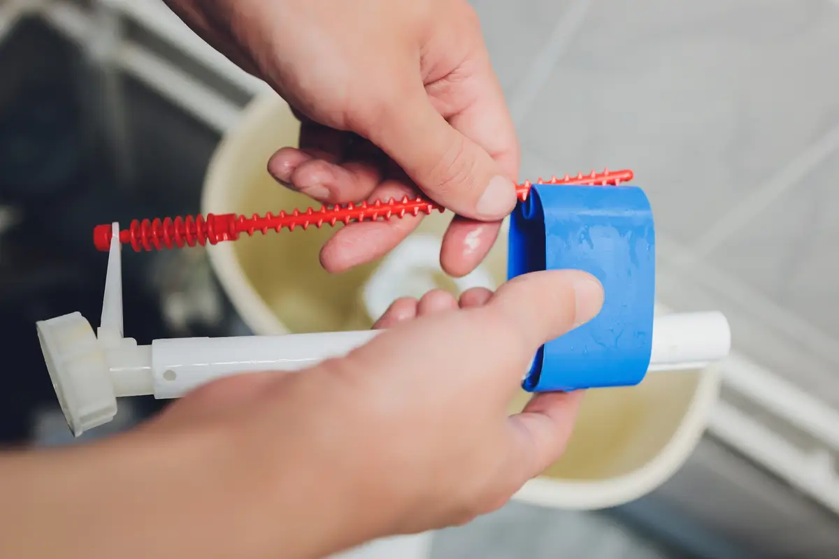 Hand is fixing a toilet cistern at home