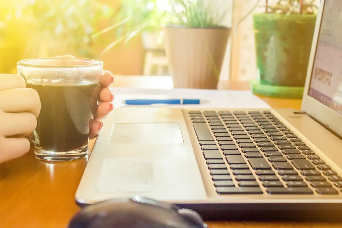 Laptop close up of a keyboard and a Cup of hot coffee in the morning. Selective focus.