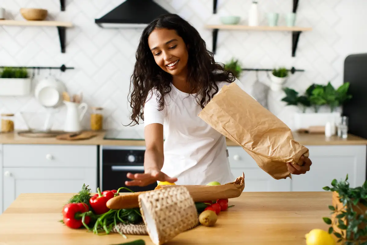 Afro girl posts products from a paper bag on the table