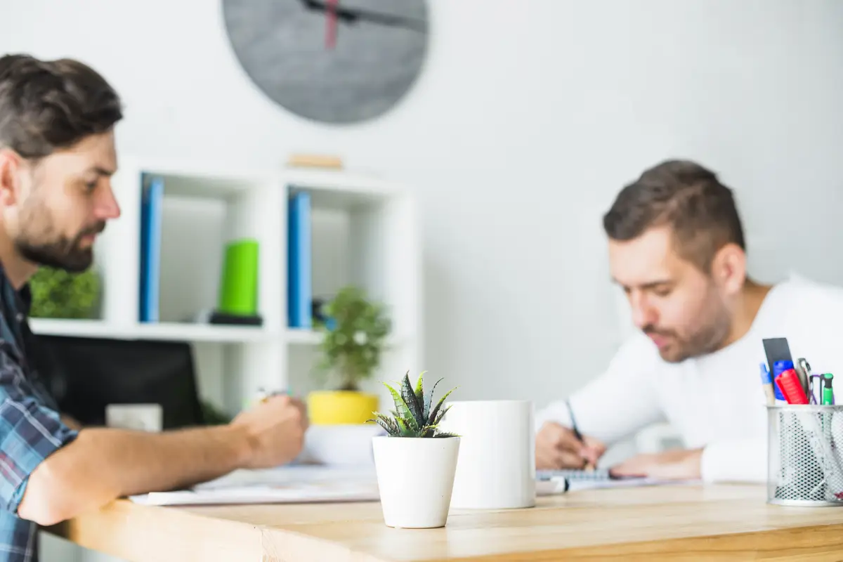 Two businessmen working over wooden desk at workplace