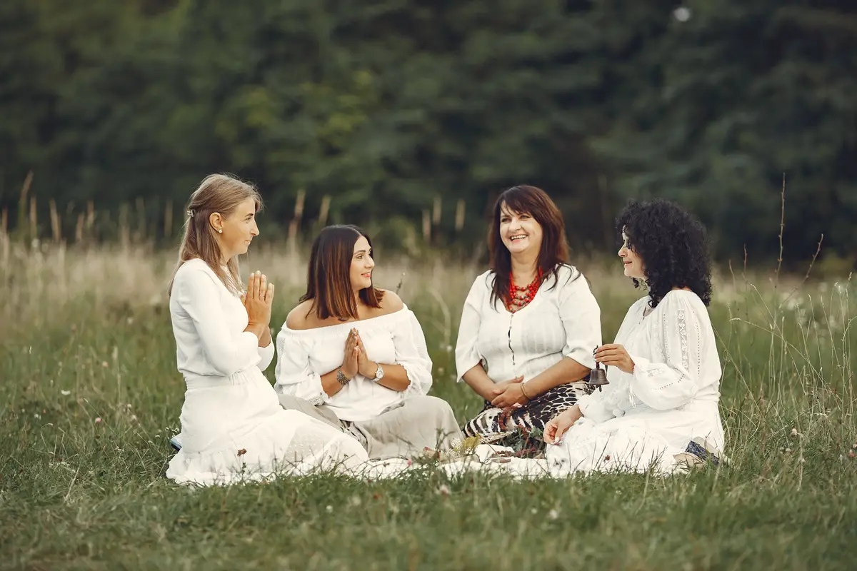 Group of women meditating together on meadow