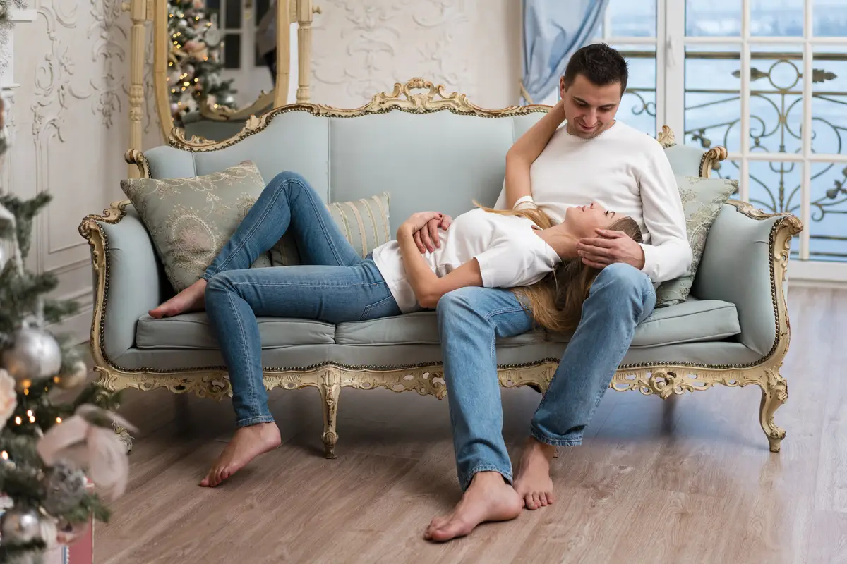 Couple posing on couch with christmass tree