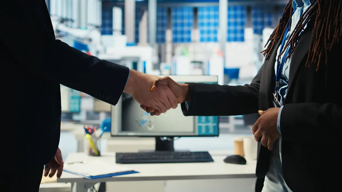 Entrepreneurs shaking hands in solar panel manufacturing plant after reaching agreement for