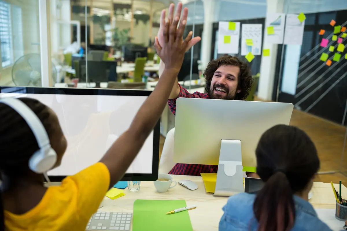 Male graphic designer giving high five to his coworker