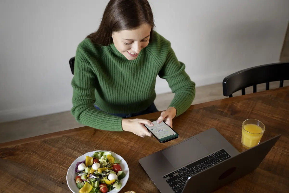 Woman looking at her smartphone while eating her meal