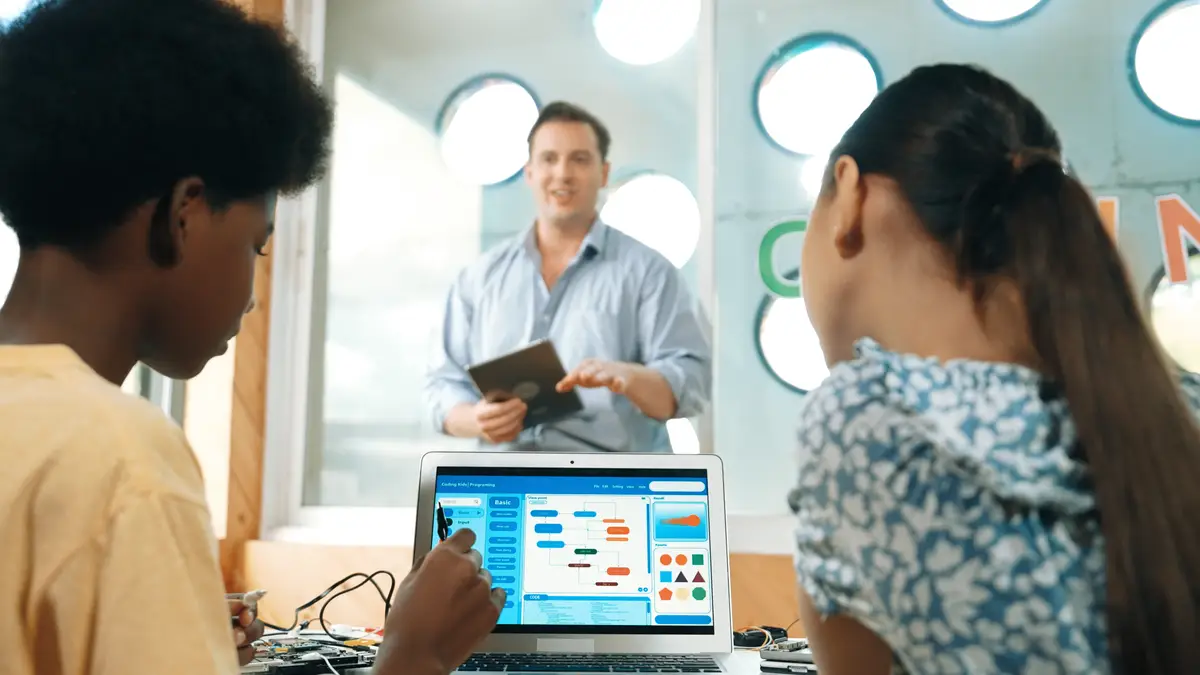 Smart teacher hold tablet while back view student learning code Edification