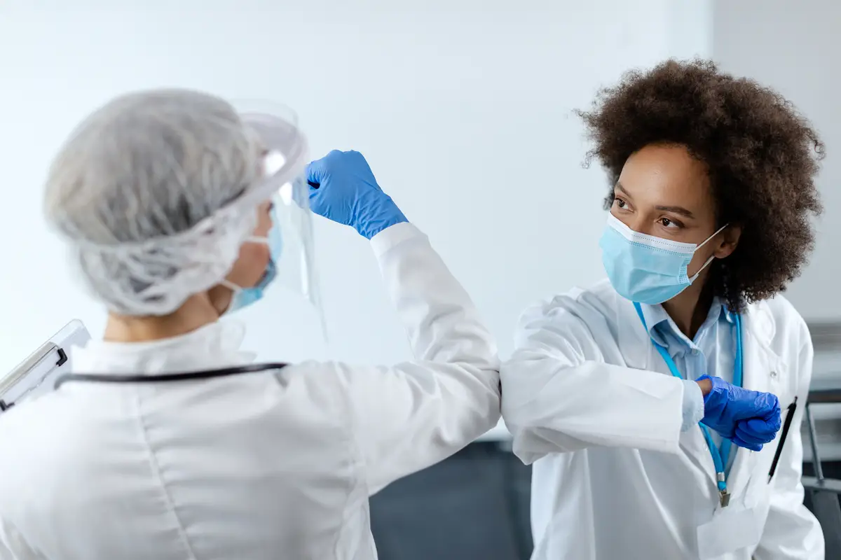 Nomenclatura e características clínicas dos estreptococos de A a G 2 African American doctor elbow bumping with her colleague at medical clinic