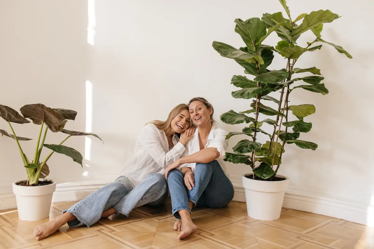 Positive caucasian blonde girls of different ages sit on floor in empty room against white wall. Concept of enjoying weekend, vacation