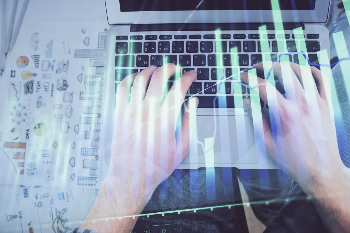 Doble exposición de manos de hombre escribiendo en teclado de laptop y gráfico forex holográfico. Vista superior. Concepto de mercados financieros