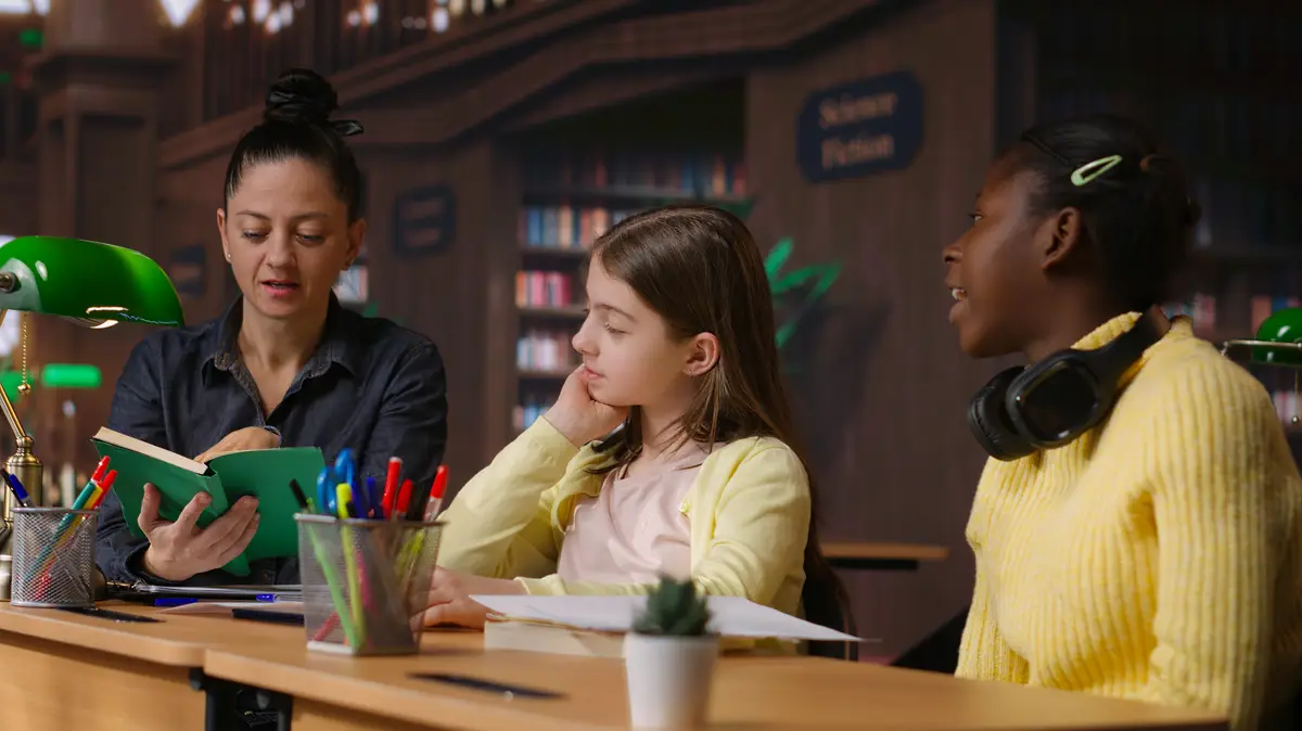 Female tutor mentoring schoolgirls in a school library setting