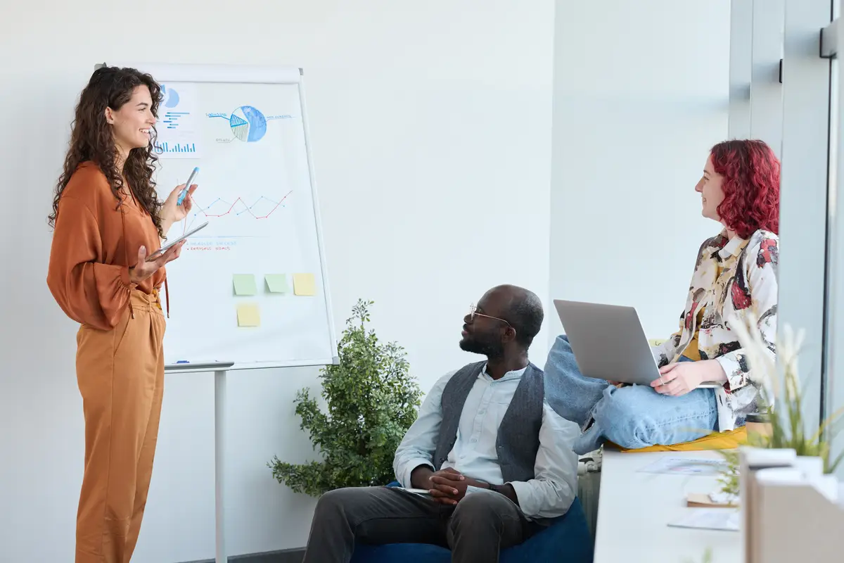 Young confident businesswoman standing by whiteboard with diagrams