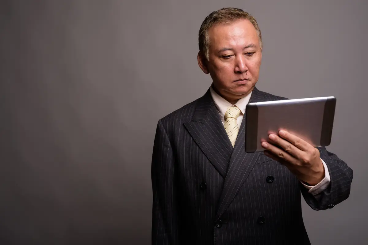 Mid adult man using smart phone against gray background