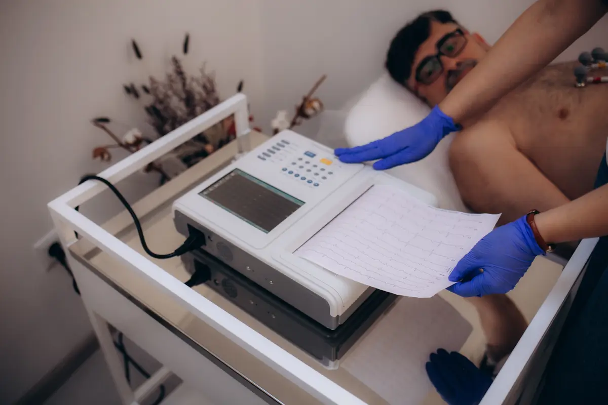 A female doctor is doing a cardiogram of an older mans heart