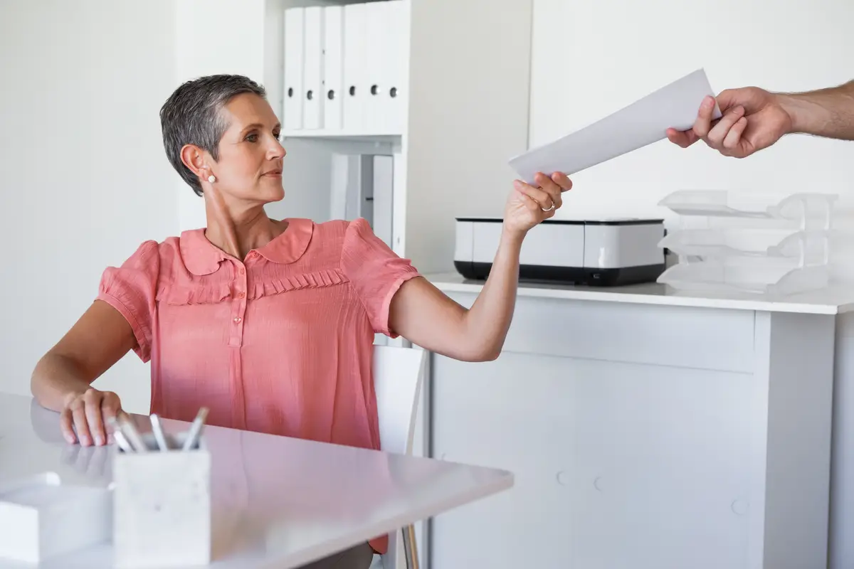 Casual businesswoman handing document to colleague