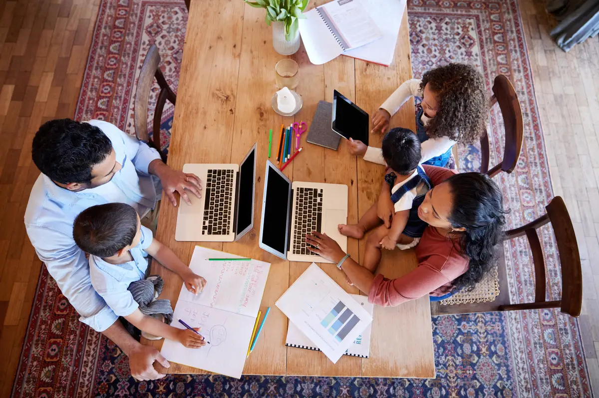 Above laptop and family in home for e learning streaming and online or videos for education Children parents and technology at table in apartment for teaching studying and together in morning